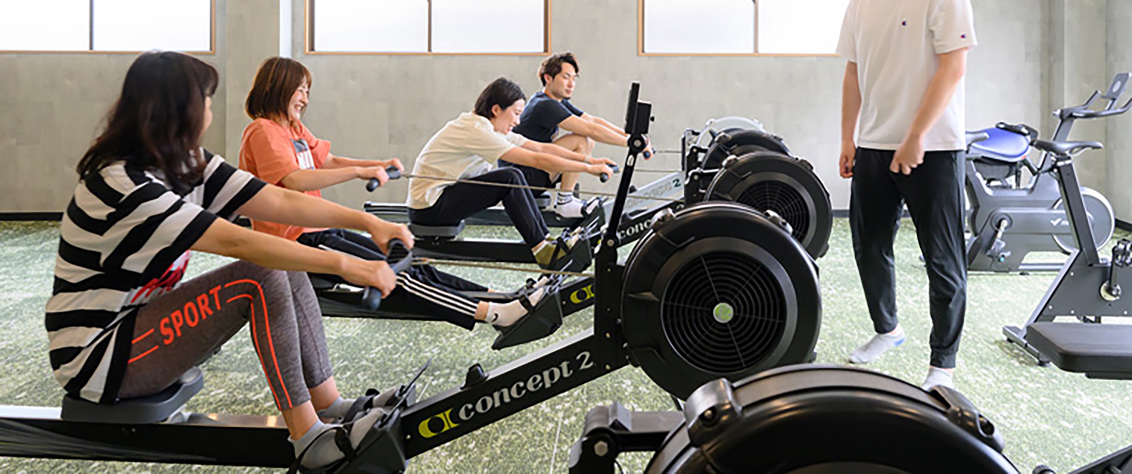 トレーナーとローイングマシンで練習する様子